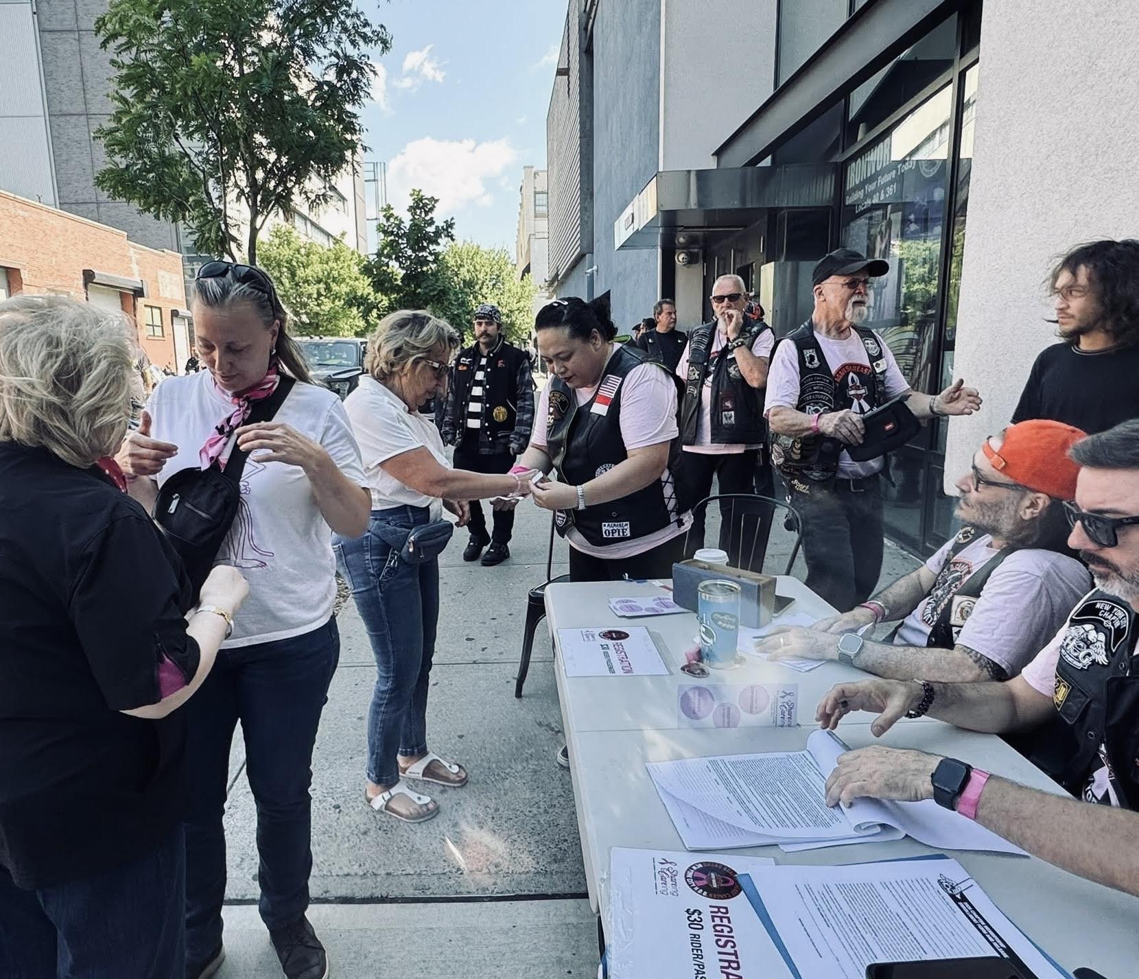 Women and men in motorcycle jackets in front of a registration table