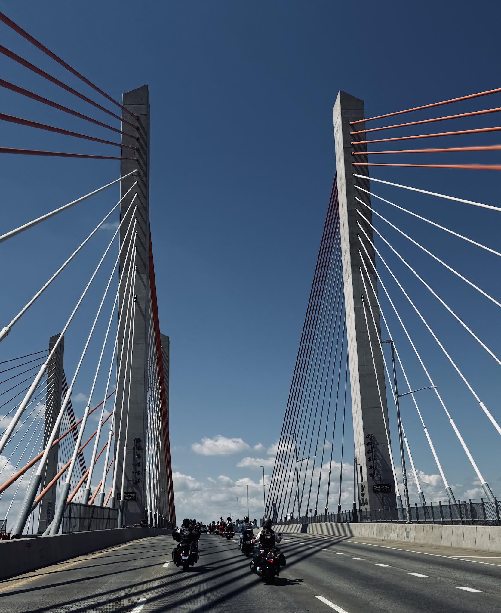 A line of motorcycles on a suspension bridge