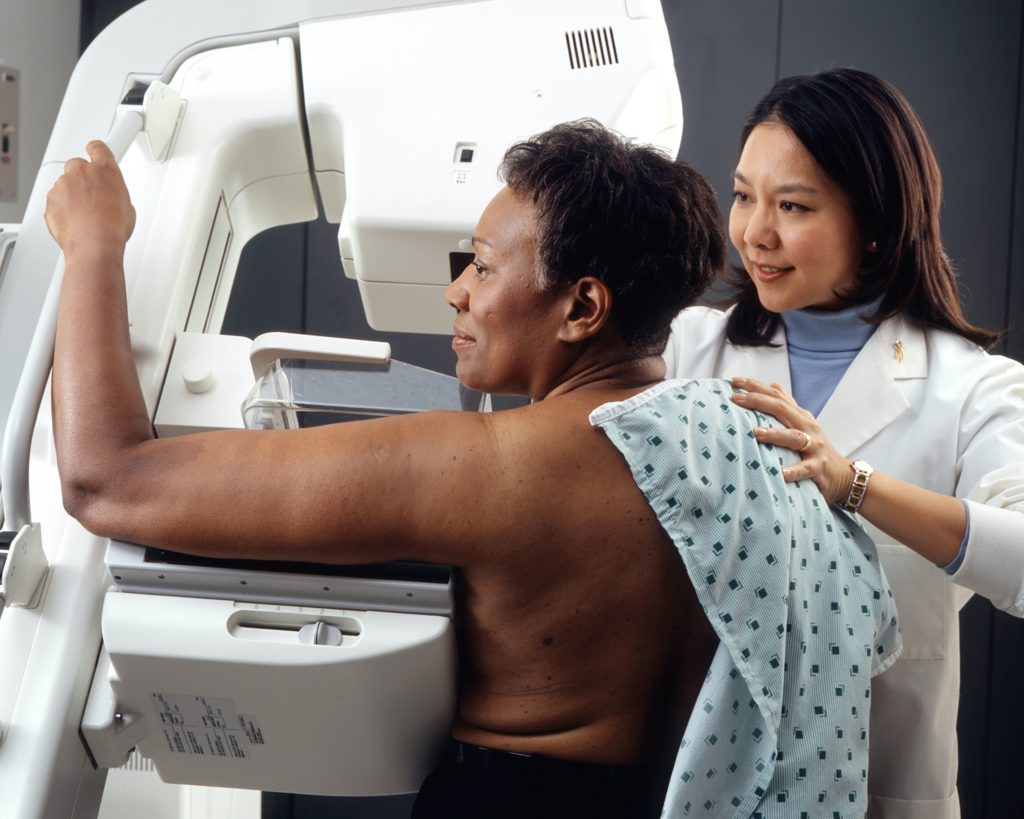 nurse helping patient with mammogram machine